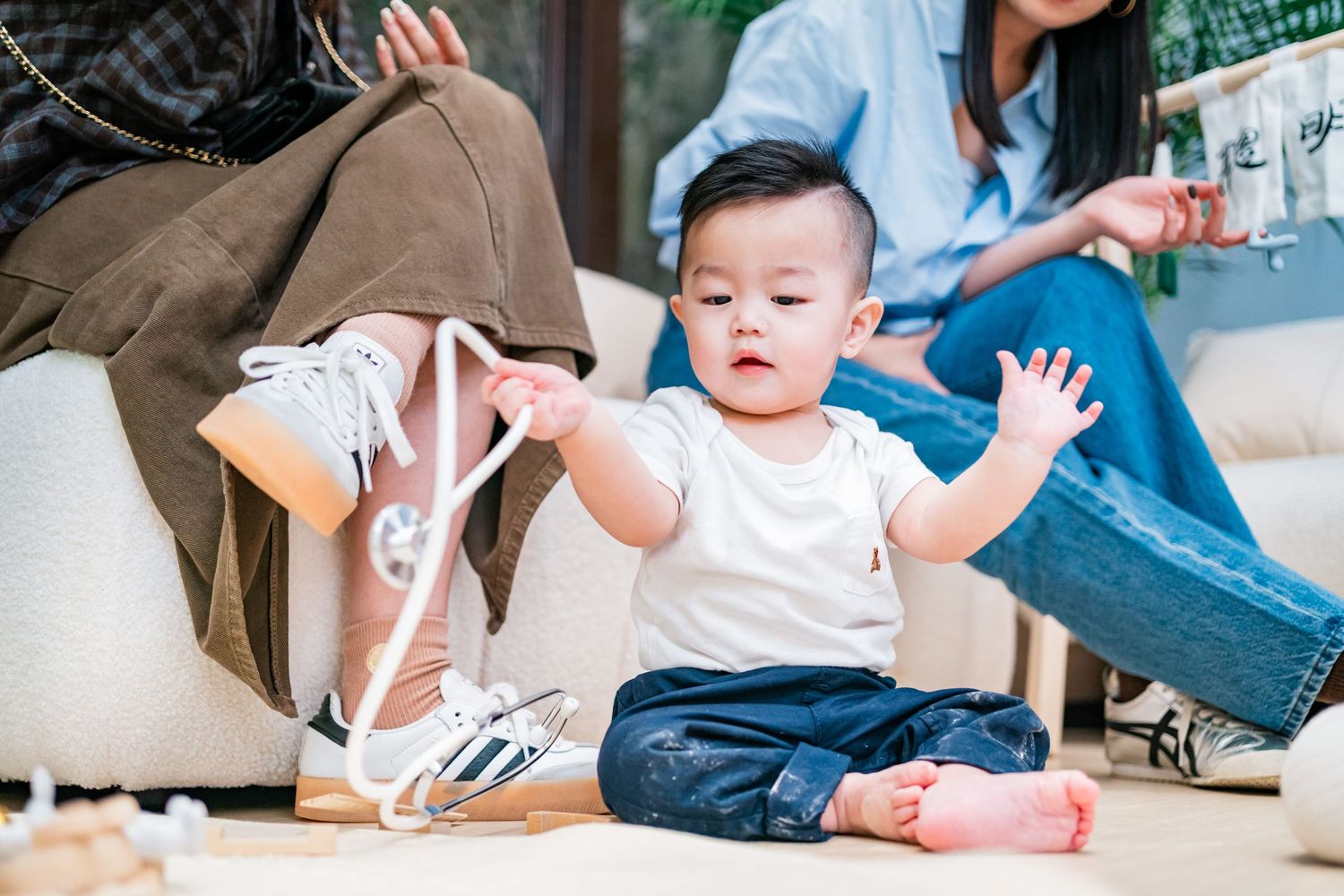 Baby wearing blue shirt plays and learns on floor mat with parent during developmental activities at home.