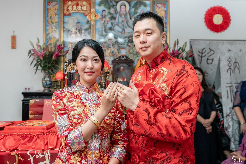 Traditional Chinese tea ceremony with decorative backdrop and red outfits.
