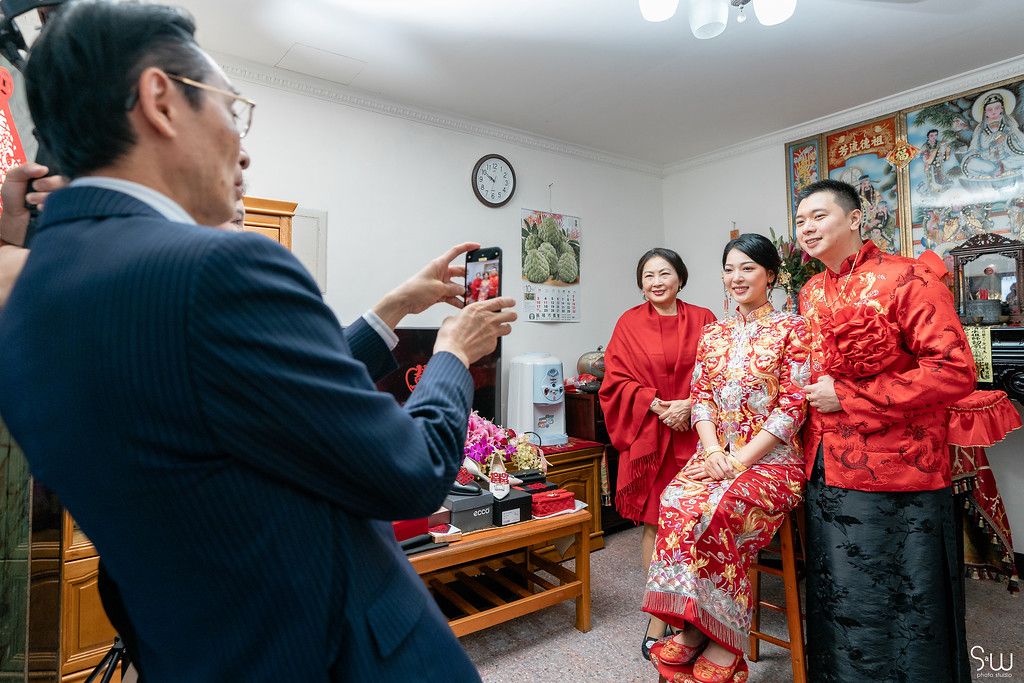 Indoor wedding celebration with family members in formal attire during Chinese ceremony.
