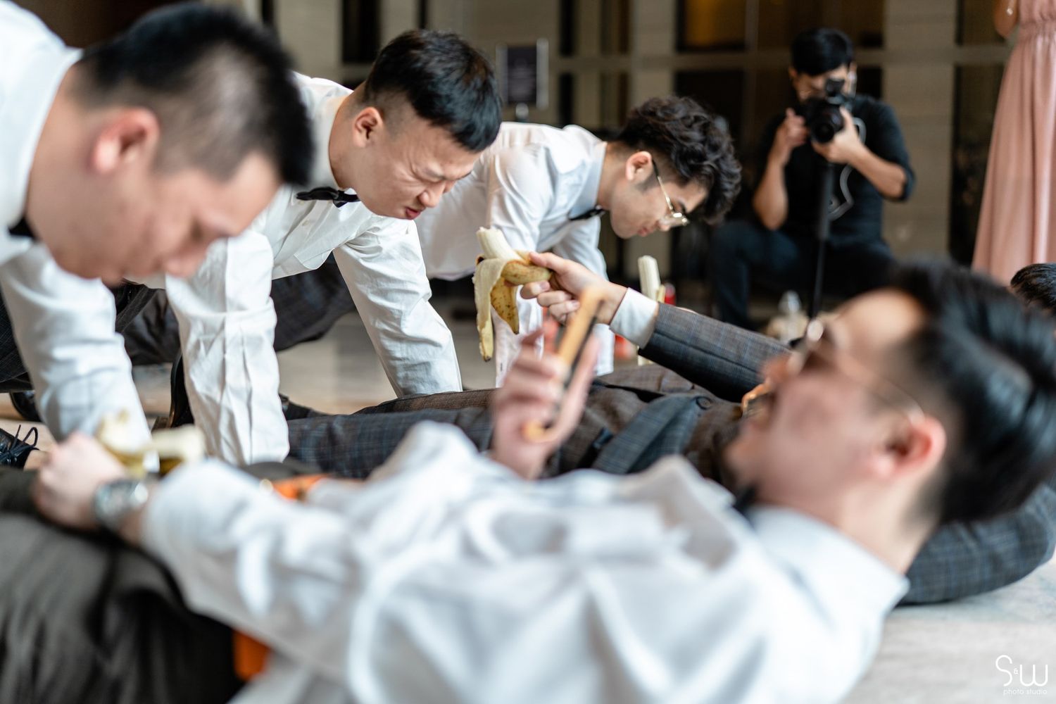 Groomsmen in white shirts playfully celebrate during wedding preparations.