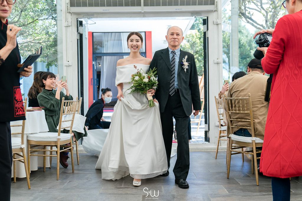 Wedding processional down aisle in modern venue with white and gold decor.