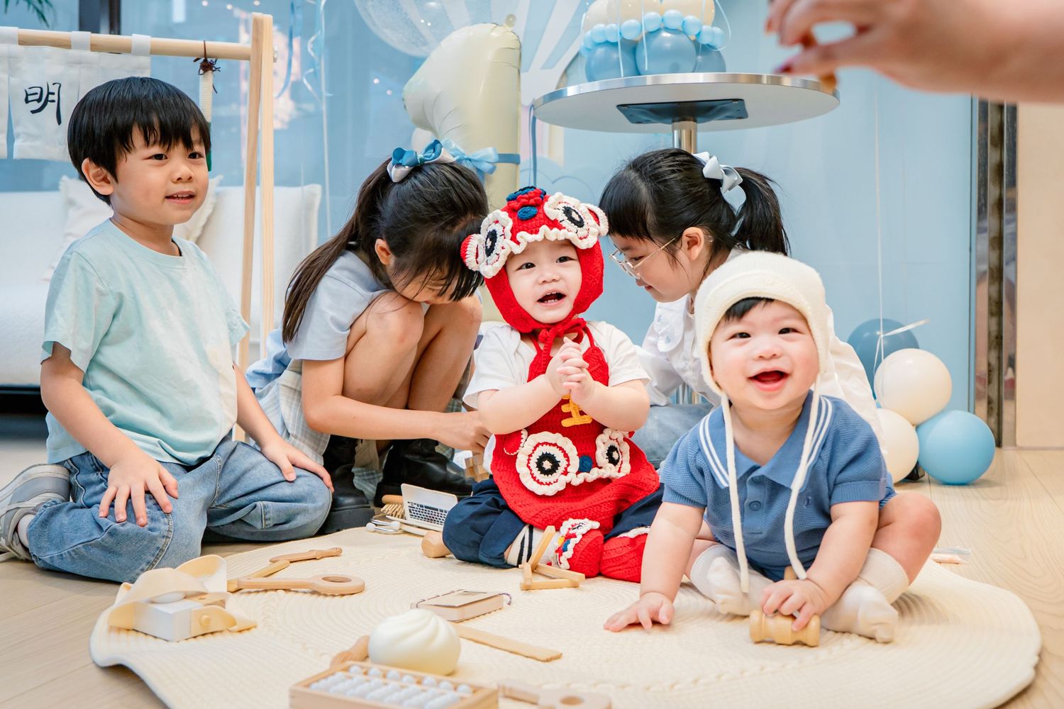Young children sit on the floor working together on a creative activity with paper and art supplies.