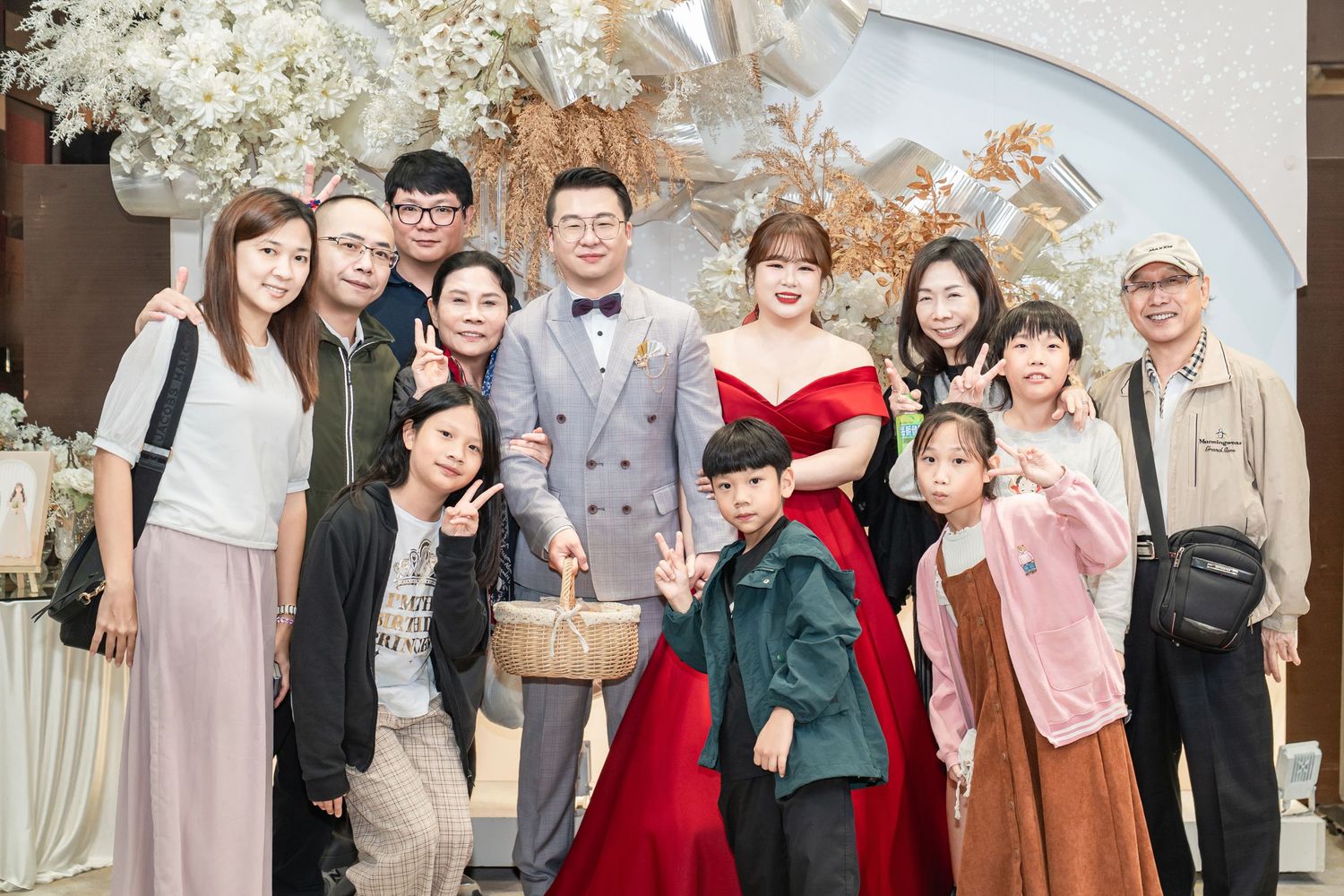 A group of guests gather at an elegant wedding reception venue with floral decorations and formal attire.