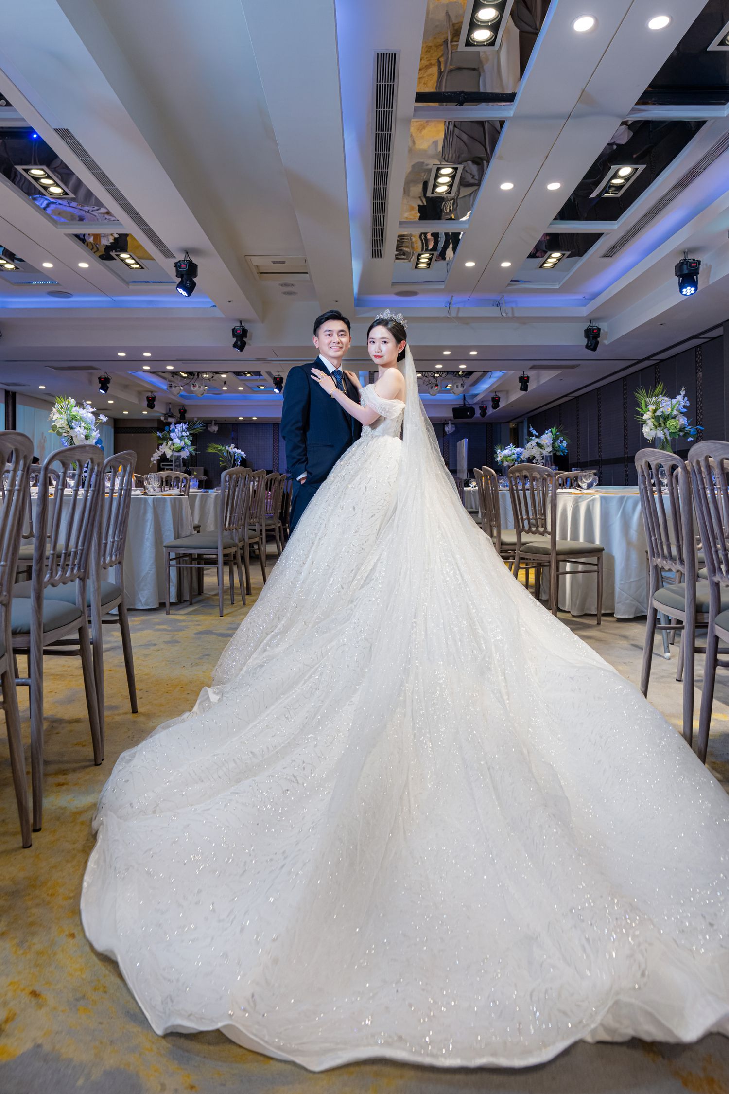 Elegant white ballgown wedding dress with long train displayed in luxurious bridal boutique showroom with modern lighting.