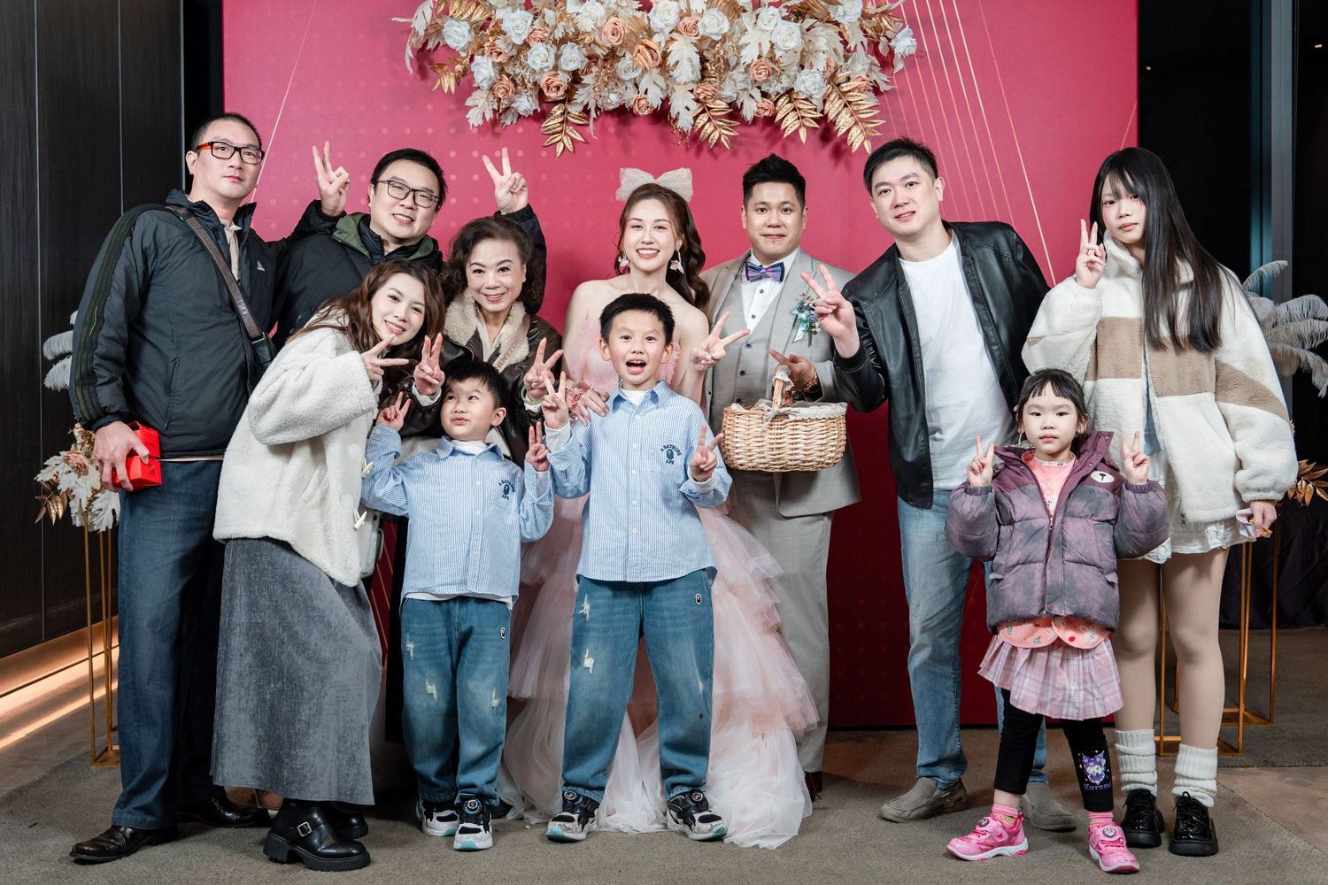 Group photos of people celebrating at an event with a pink backdrop and elegant chandelier lighting.