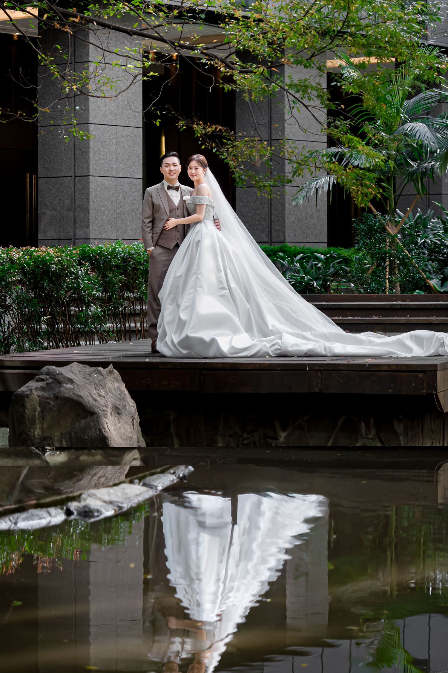 A stunning wedding photo shows a couple on a wooden deck with the bride's white gown beautifully reflected in a pond below.