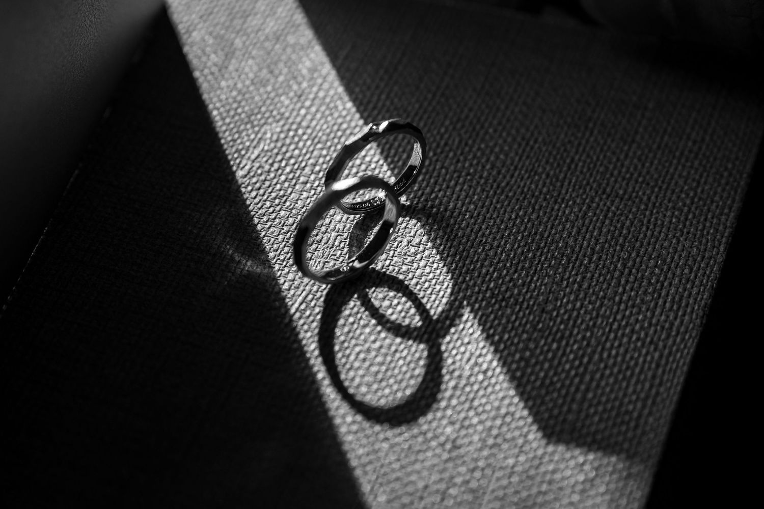Three dark rings cast dramatic shadows on a textured fabric surface in black and white photography.