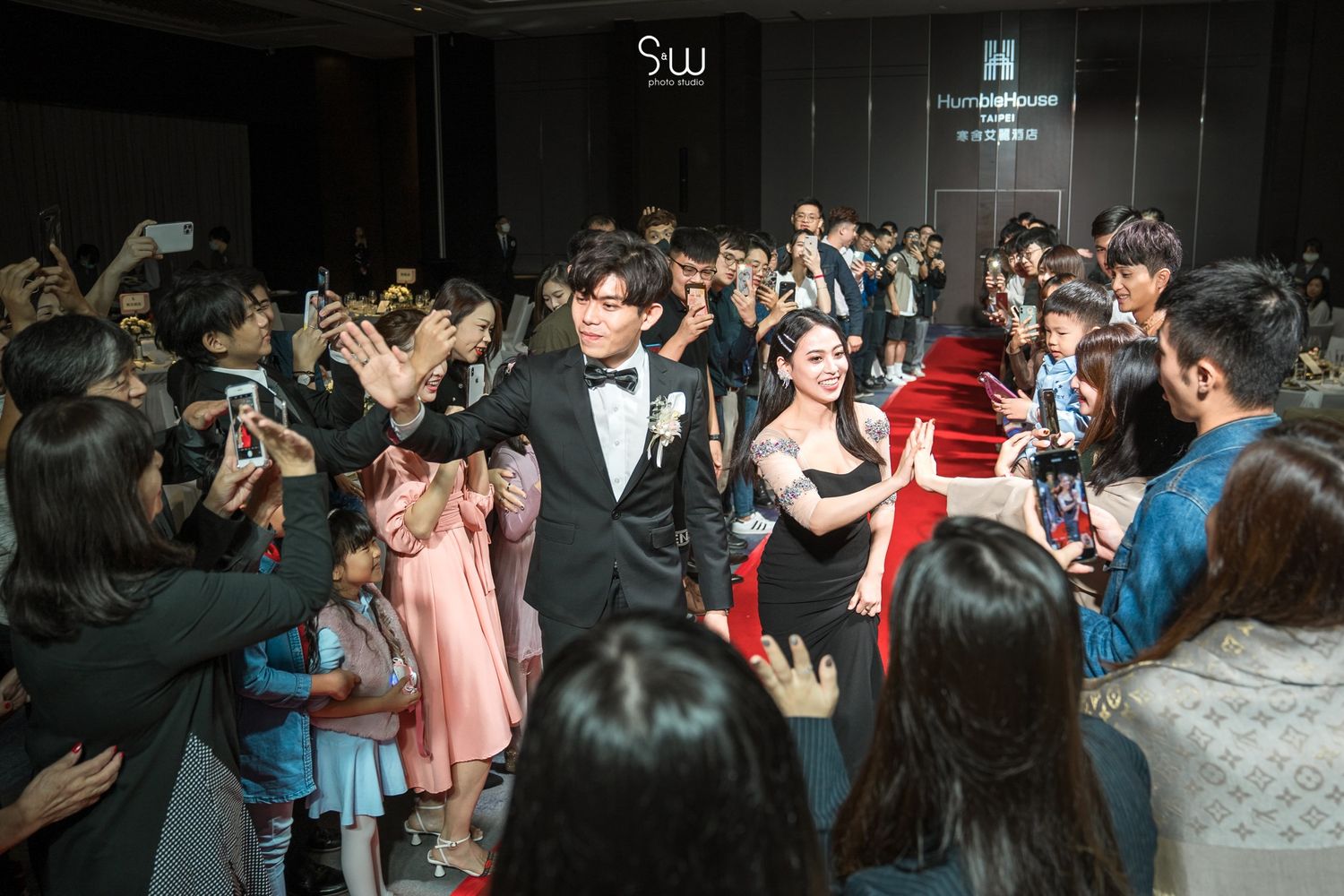 Wedding celebration with guests taking photos of the couple on a dance floor.