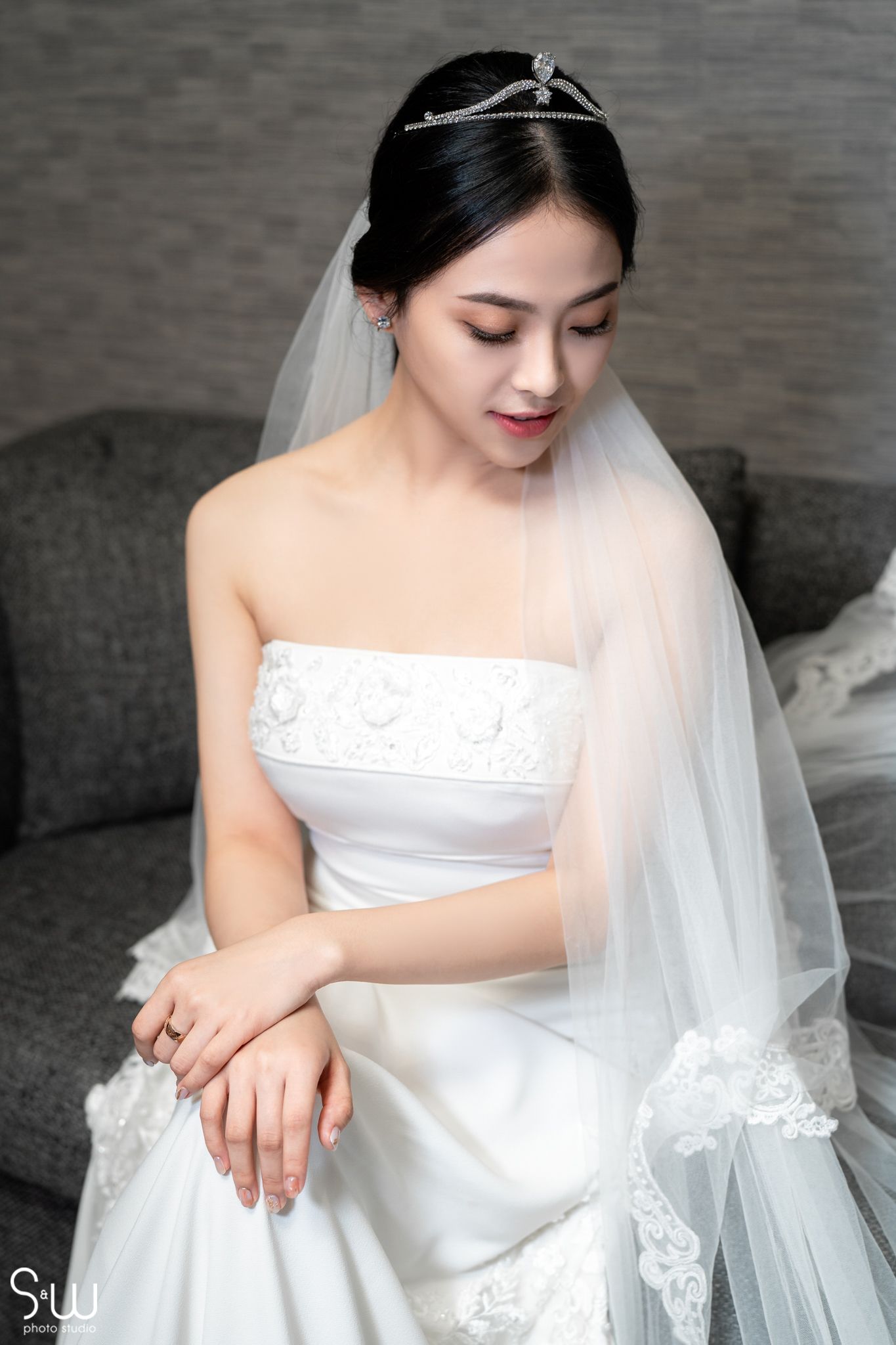 Close-up of bride wearing delicate veil and strapless white wedding dress.