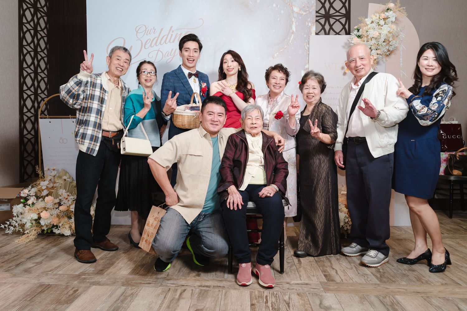 A group of formally dressed party guests gather together in a festive room with Christmas decorations and smile for a photo.