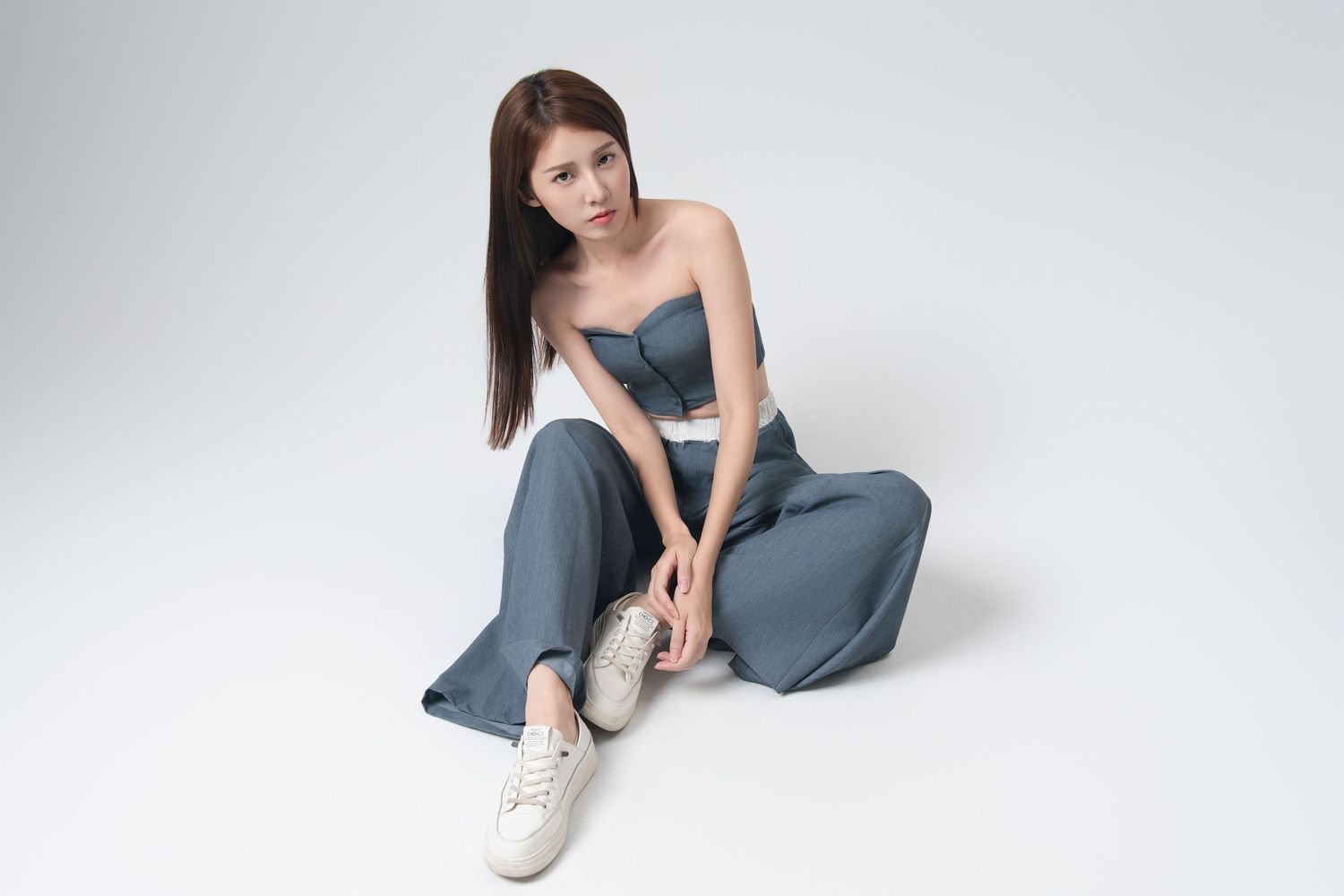 Model in gray loungewear and white sneakers poses in various positions against a light background.