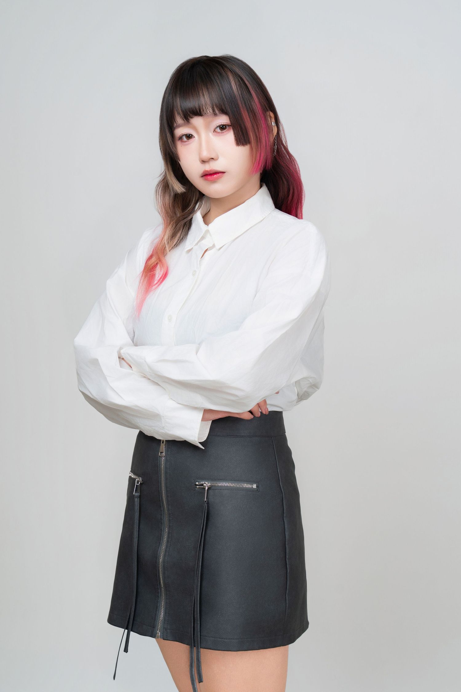Fashion model in white blouse and black leather mini skirt poses against gray studio backdrop in four different poses.