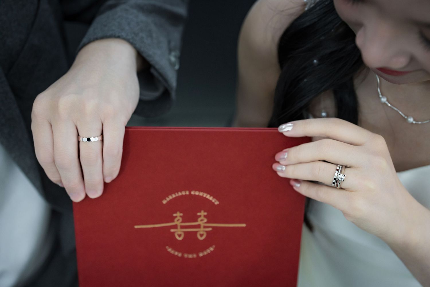 A close-up view of hands opening a red book or album with gold lettering on the cover.