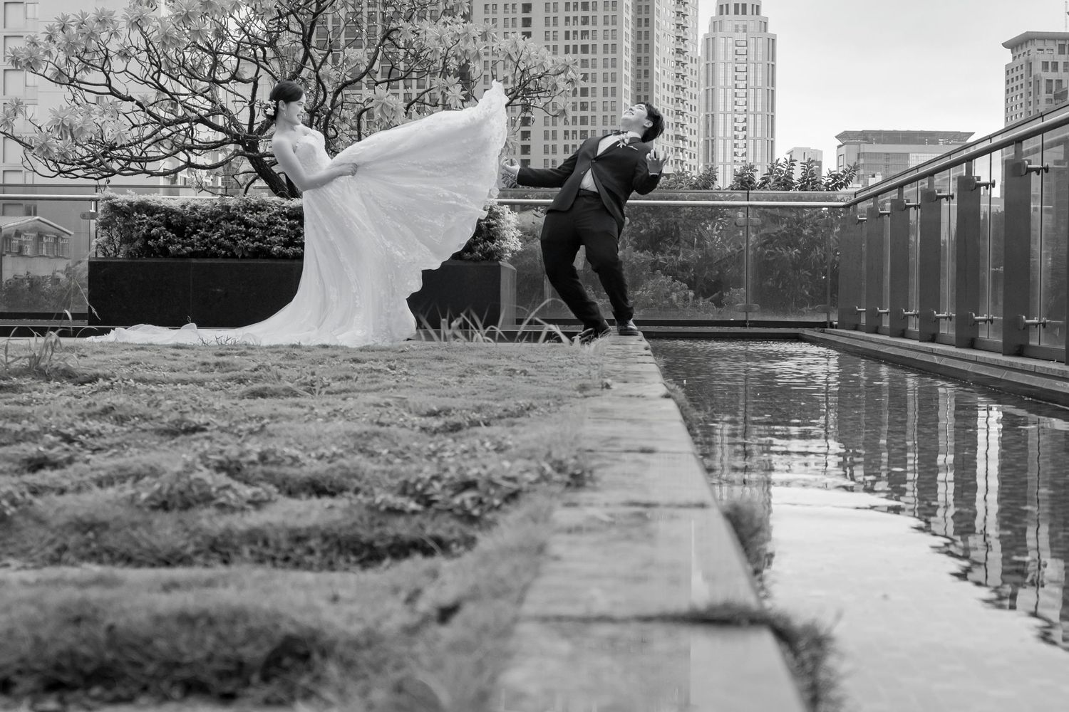 A series of black and white wedding photos showing a couple in romantic poses by a city waterfront.