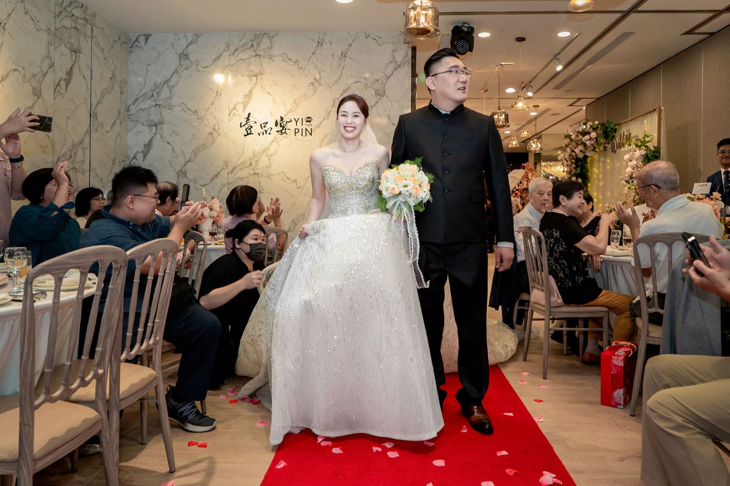 A wedding reception venue with elegant decor features multiple tables and chairs arranged in a spacious hall.