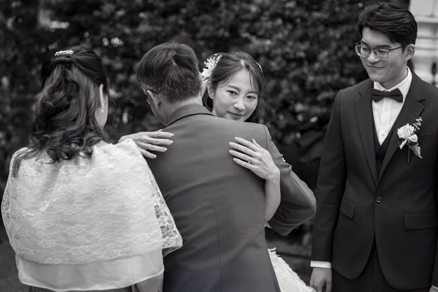 A bride and groom share an intimate moment during their wedding ceremony in a lush outdoor garden setting.