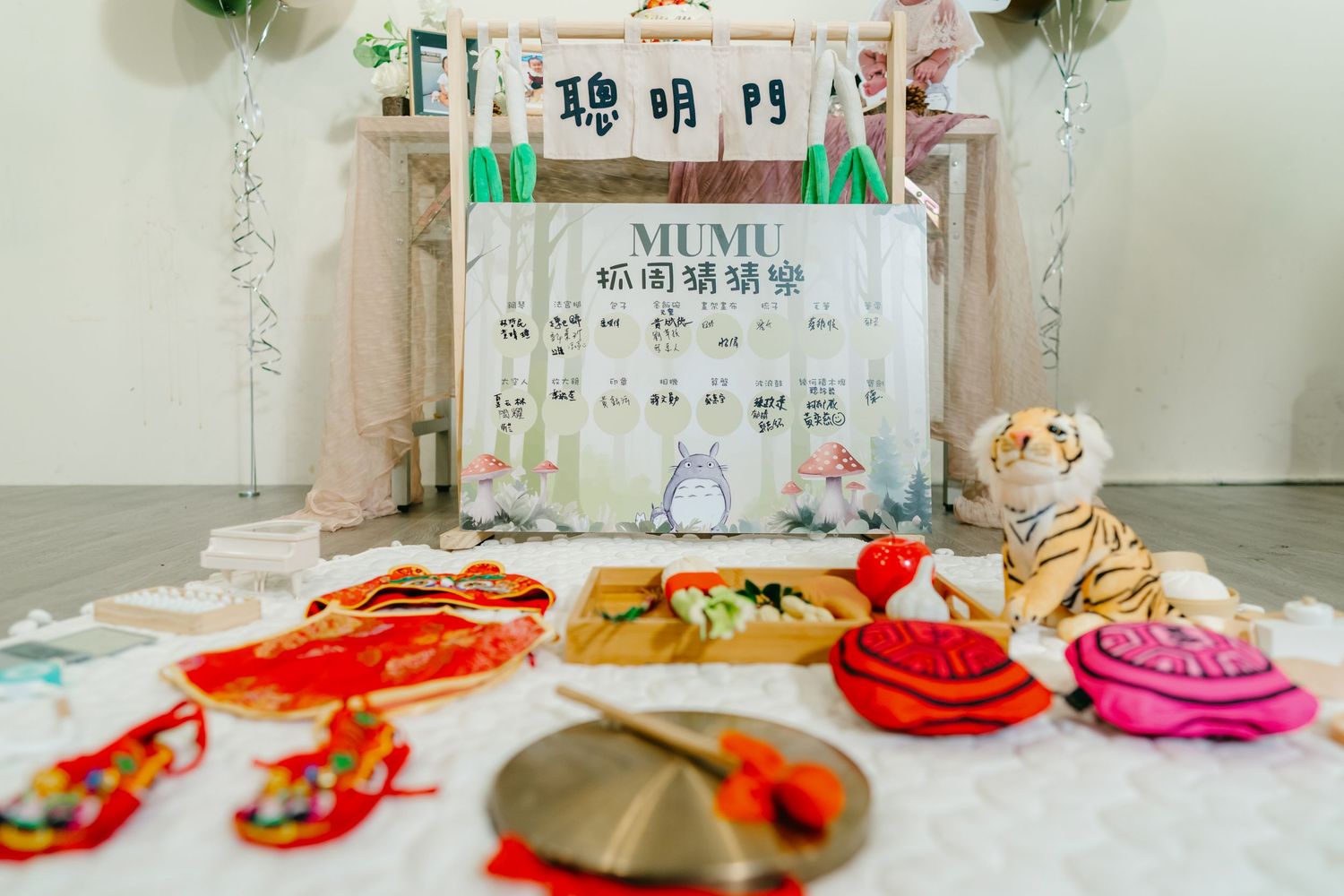 Red and pink macaron cookies arranged on a white tabletop with elegant party decorations in the background.