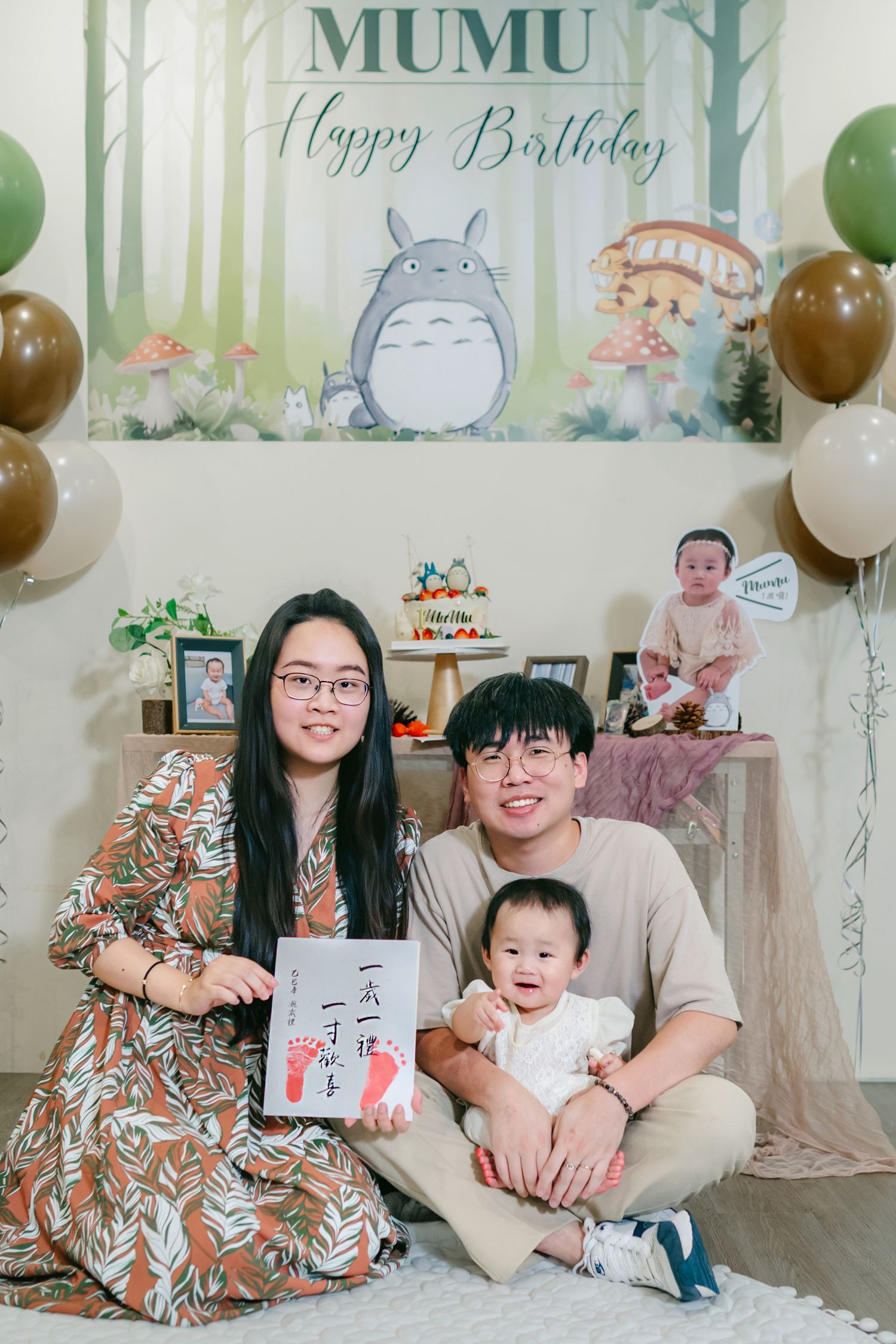 Themed birthday celebration with Studio Ghibli Totoro decorations, balloons and floral accents in green and white colors.