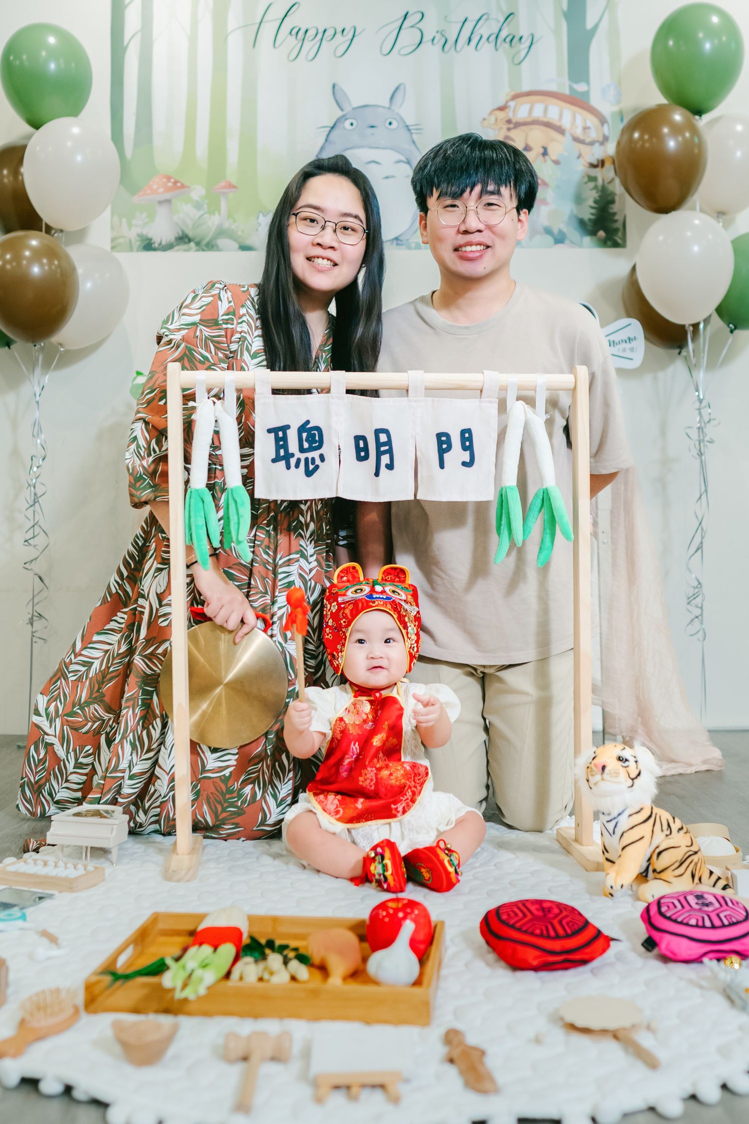 Birthday party setup with green and gold balloons, white furniture, and decorative elements for a festive celebration.