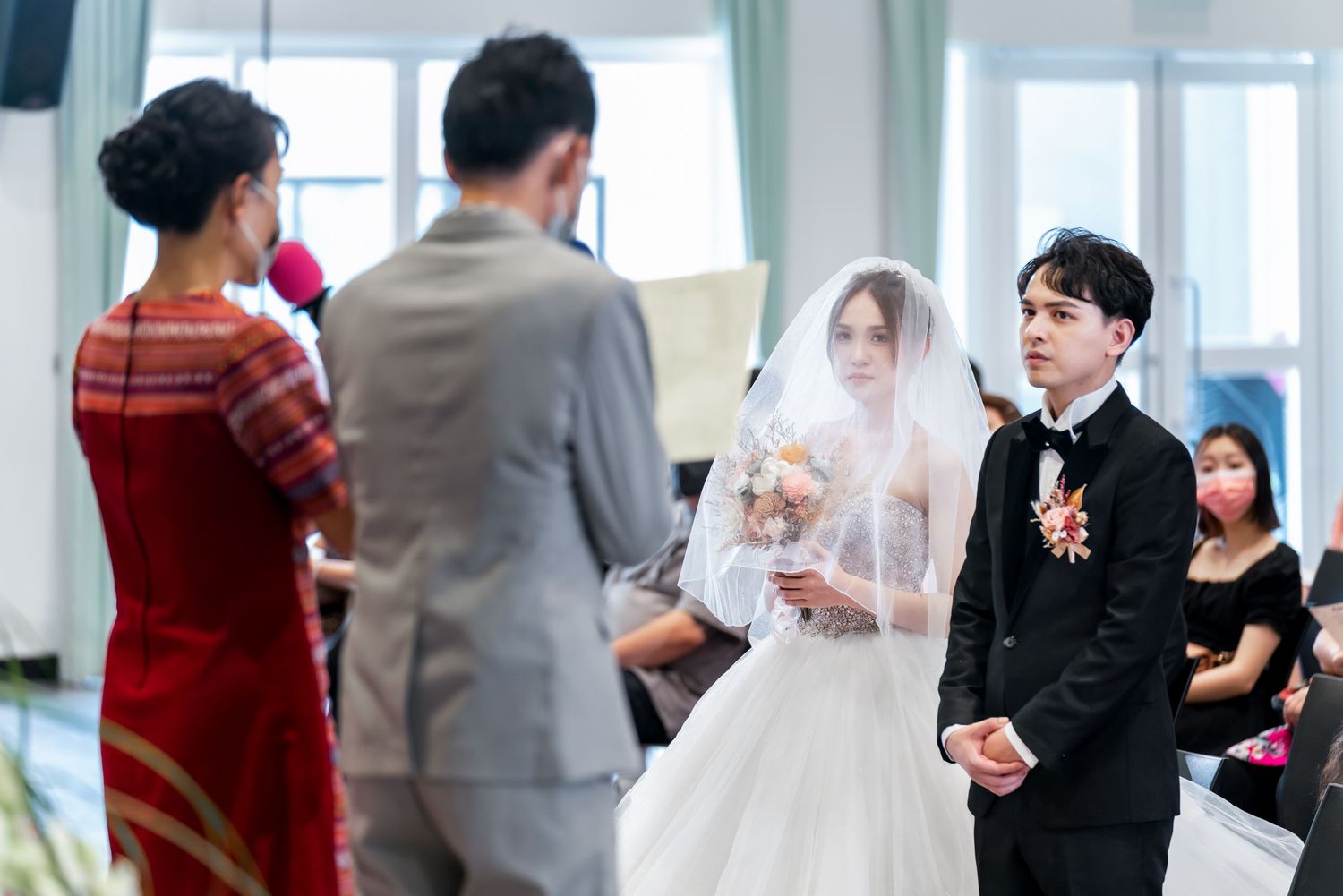 Wedding ceremony in progress with guests watching the proceedings.