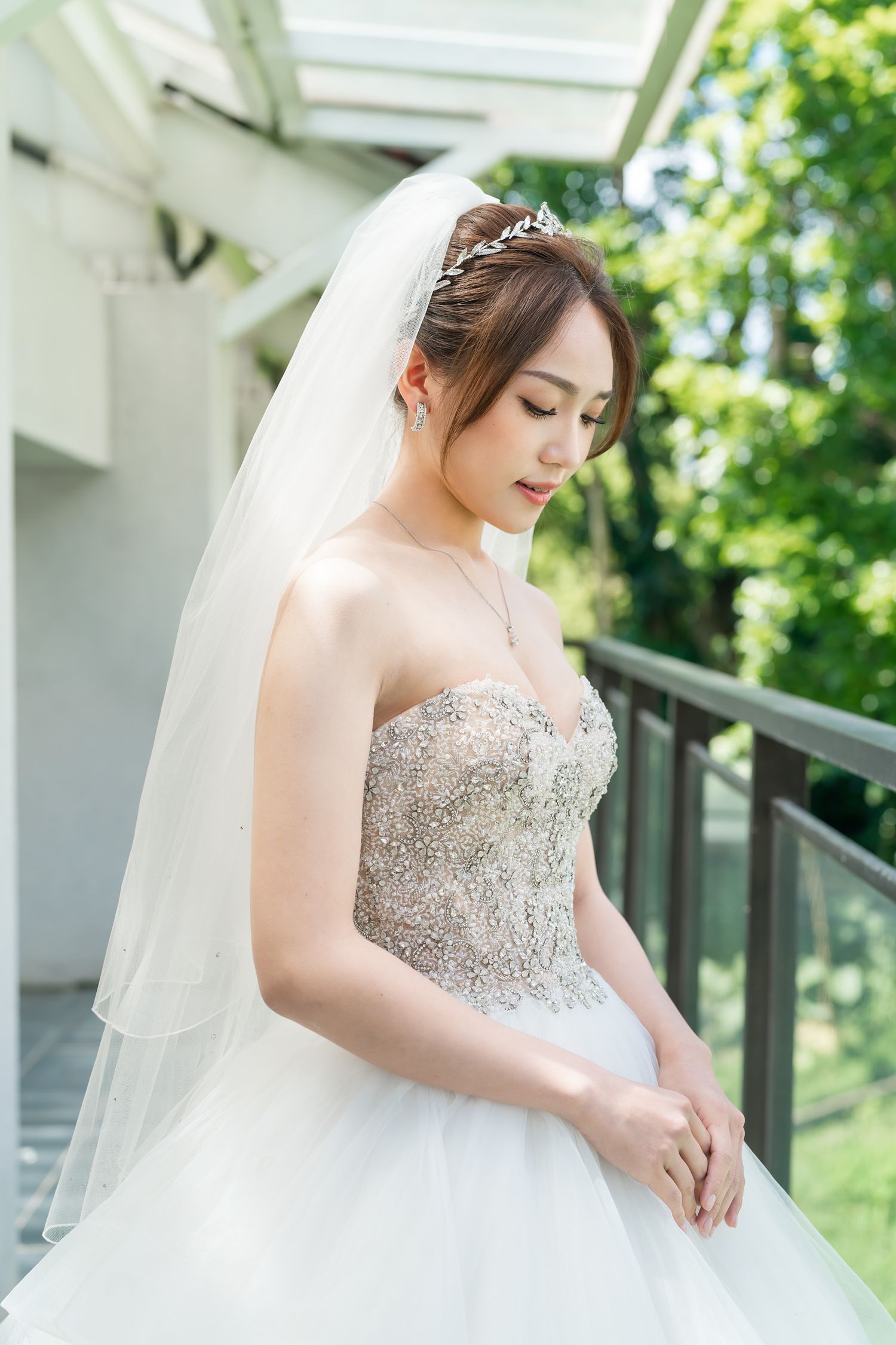 Close-up of bride wearing embellished strapless wedding gown with layered tulle skirt and long veil.