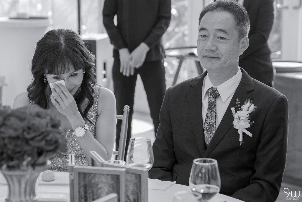 Black and white emotional moment captured during wedding reception speeches.