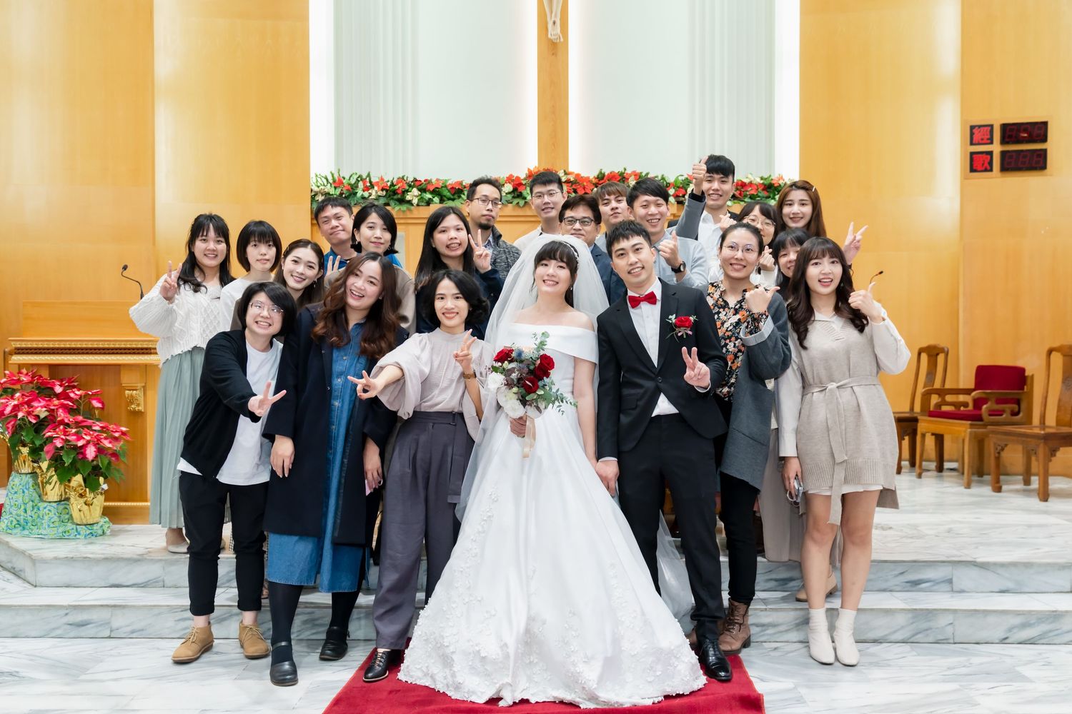 Young wedding guests pose with couple on church steps with Christmas garland.