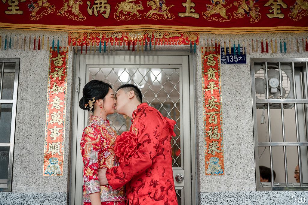Romantic moment captured between newlyweds in matching red traditional Chinese wedding attire.