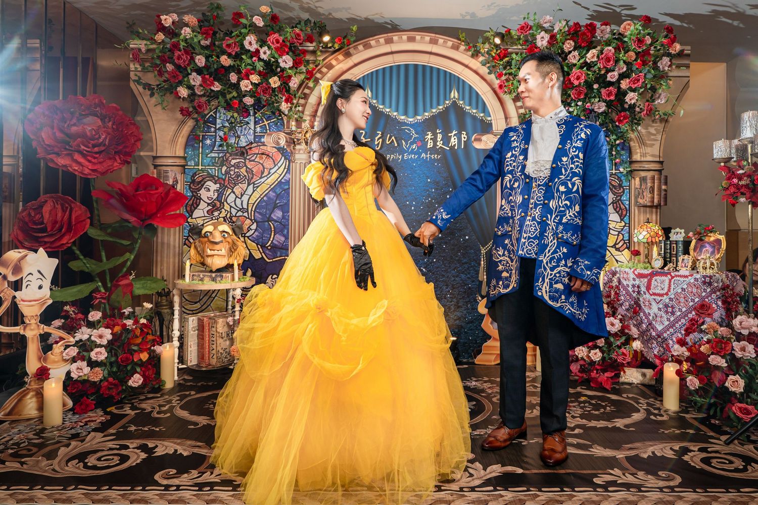 Couple in Beauty and the Beast costumes pose at a fairy tale themed wedding reception with roses.