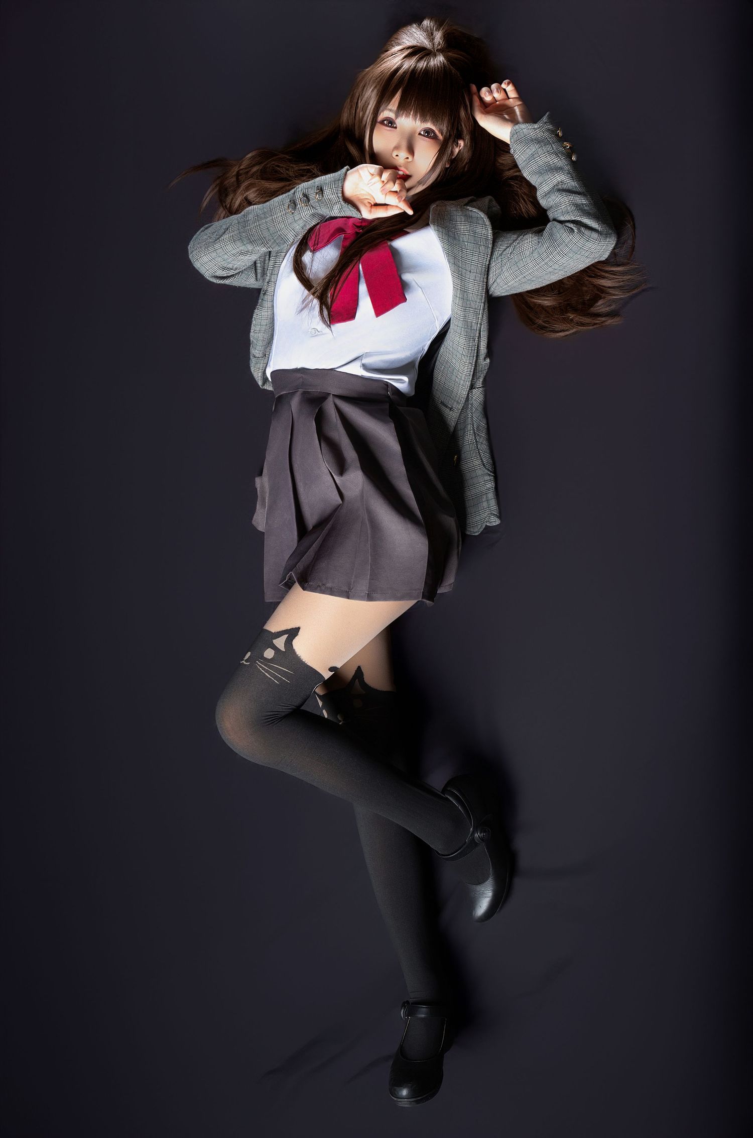 A student in a Japanese school uniform with gray cardigan and red bow strikes a dynamic jumping pose against a dark background.
