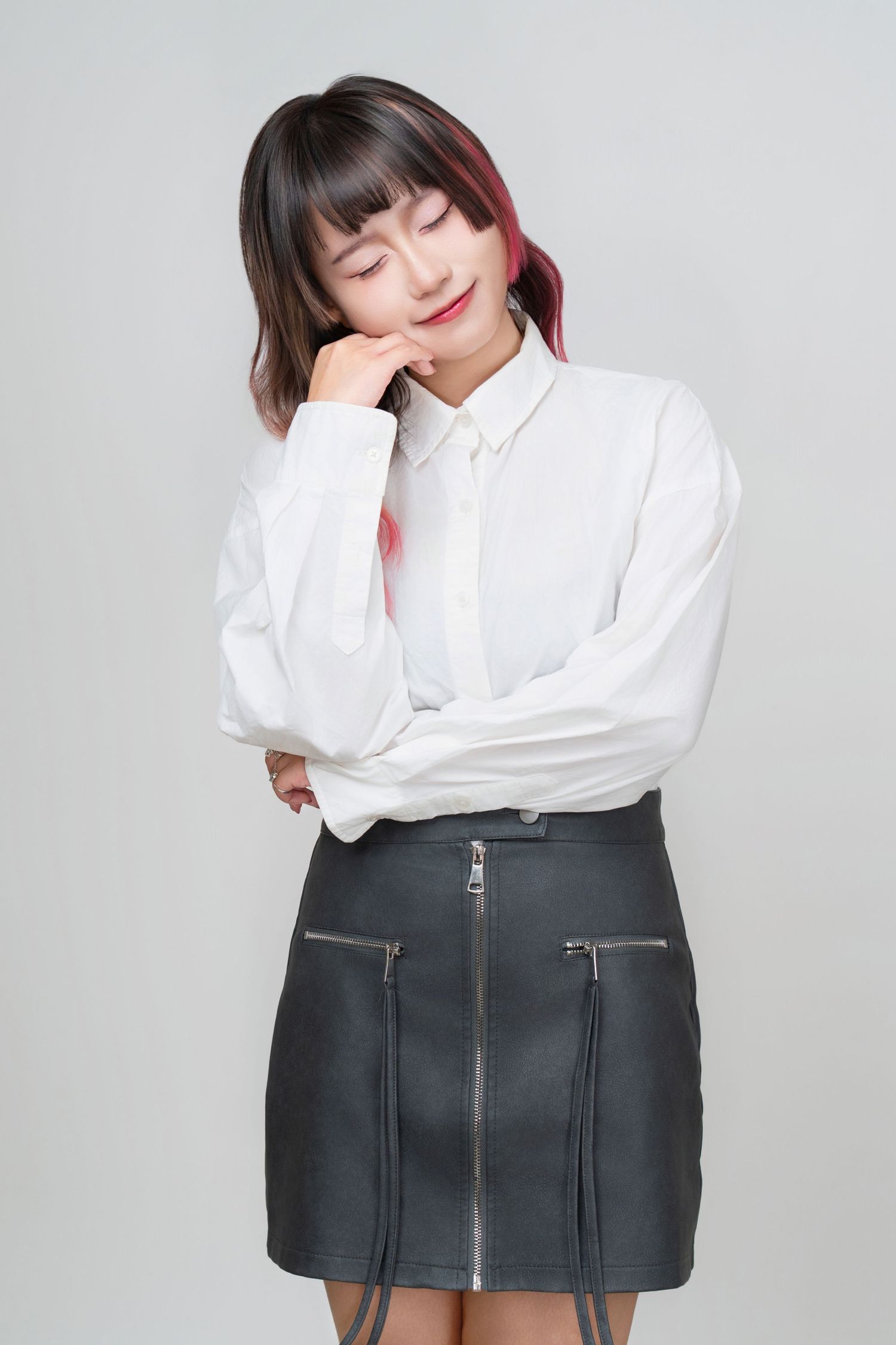 Person wearing white button-down shirt and dark mini skirt with zipper details poses in various casual stances.