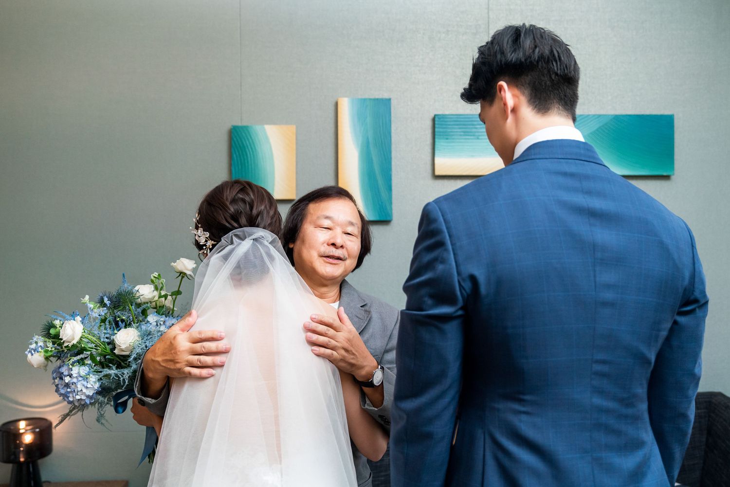 Intimate wedding ceremony moment in an indoor setting with blue decor elements and floral arrangements.