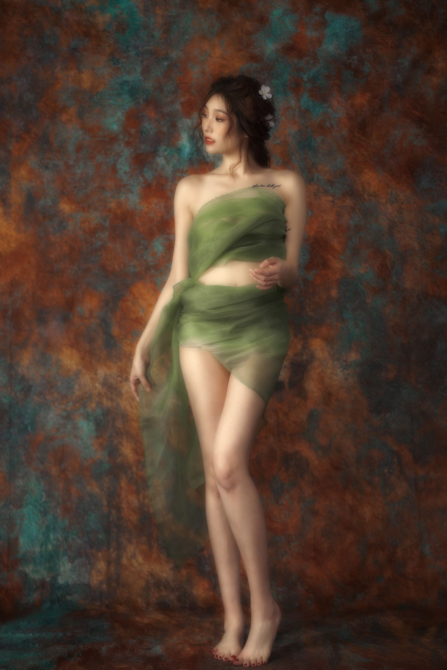Artistic portrait with draped green fabric in ethereal style against textured rust and teal background.