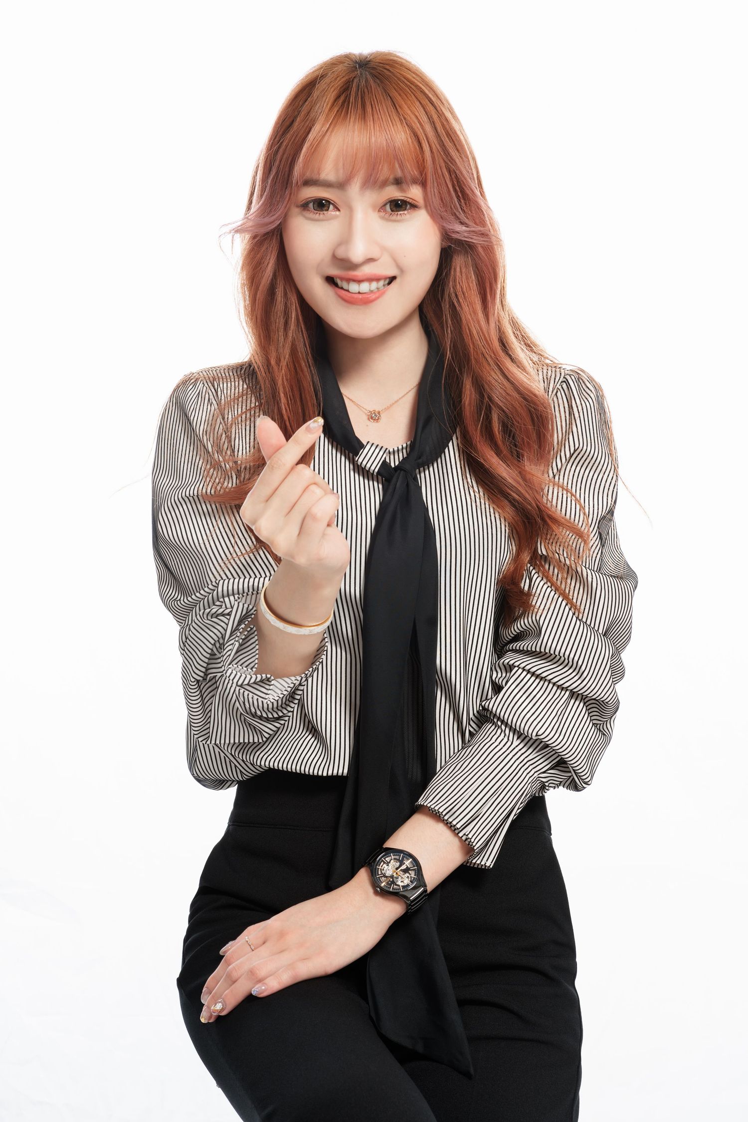 A smiling figure in a striped blazer and black tie poses against a white background with red hair and a wristwatch.