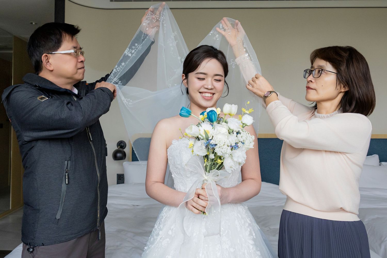 A joyful wedding celebration with dancing and embracing couples in elegant attire at an indoor venue.