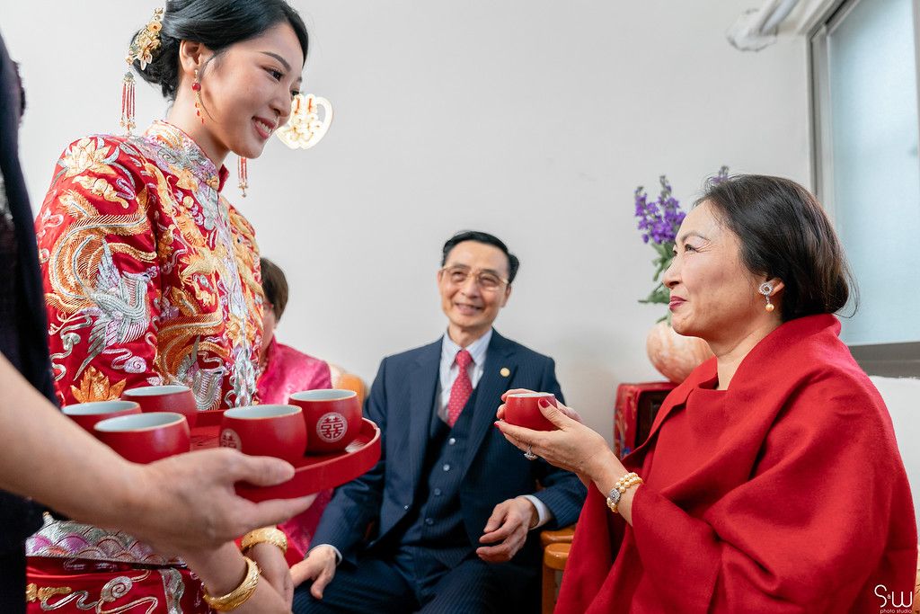 Tea ceremony exchange with participants in traditional Chinese wedding attire.