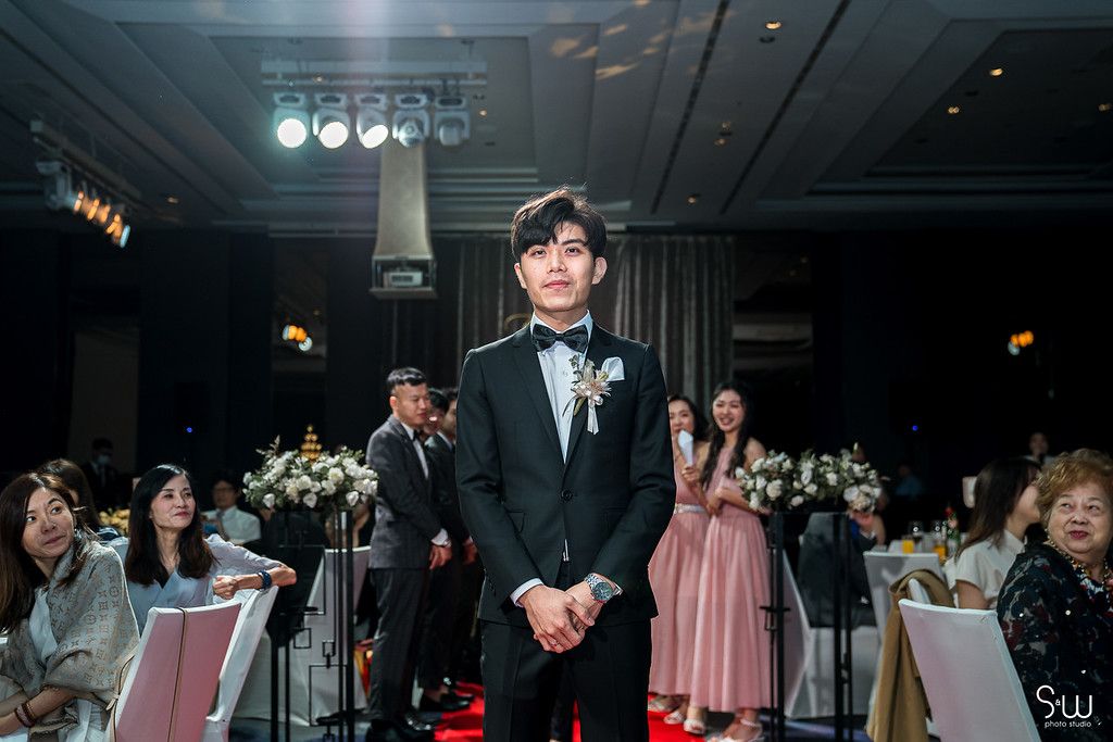A formal wedding ceremony setup with stage lighting and floral decorations in an elegant indoor venue.