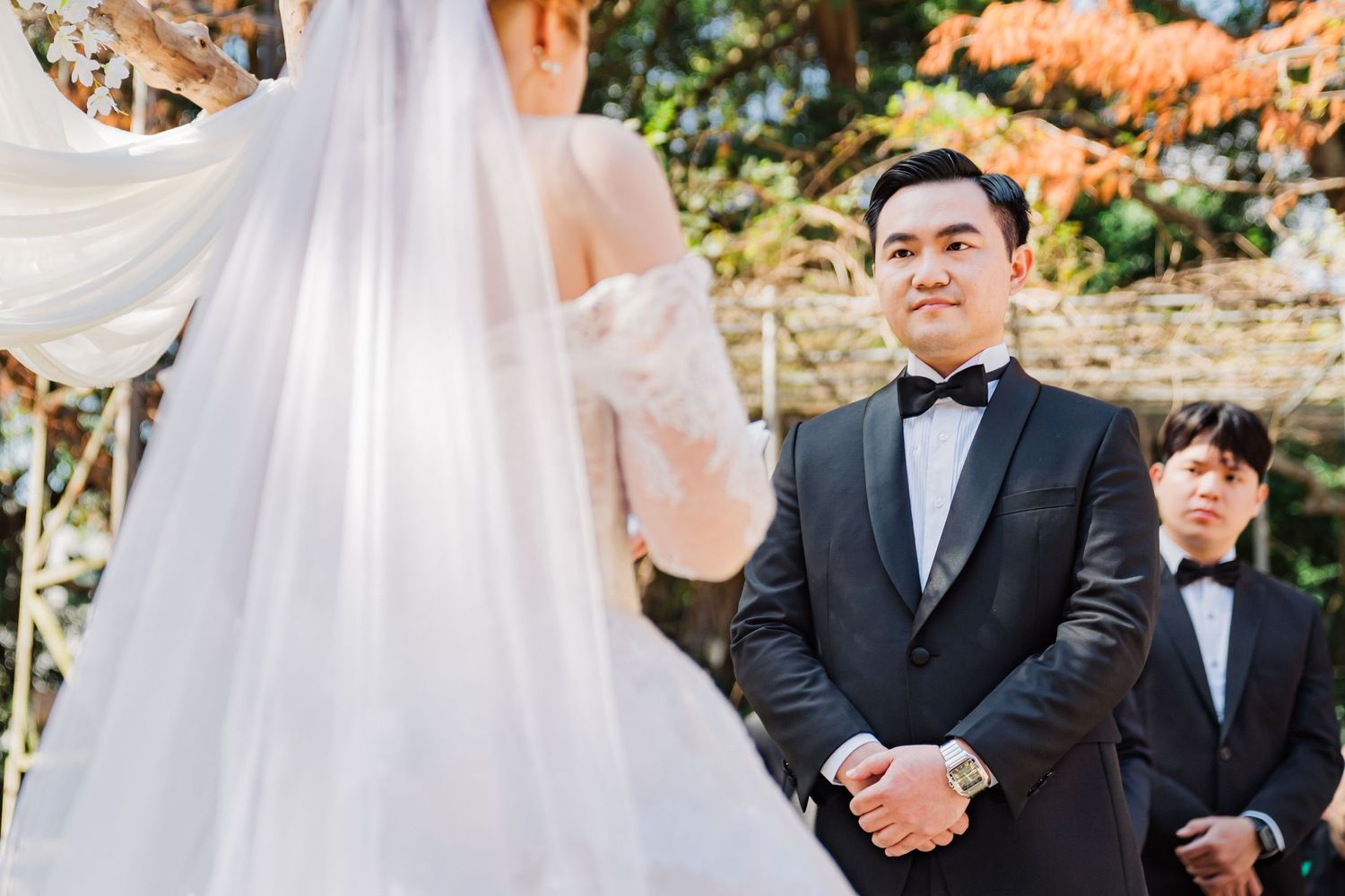 A romantic outdoor wedding ceremony with an elegant arbor decorated in fall colors.