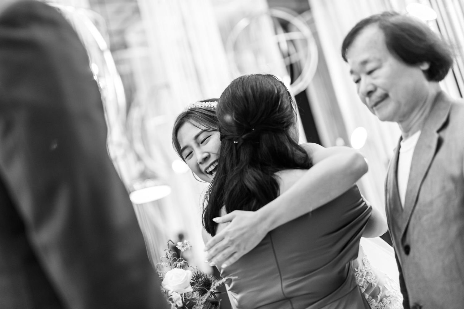 Black and white candid photo of an emotional embrace during a wedding ceremony.