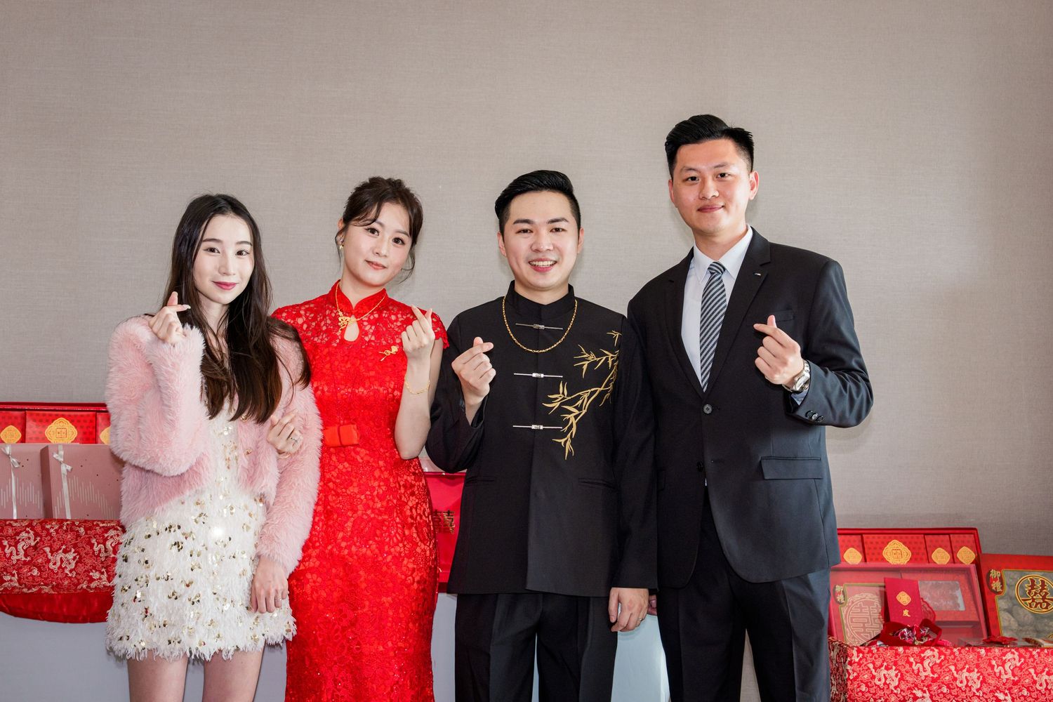 Wedding party members pose in traditional Chinese red and white formal attire during a celebration.