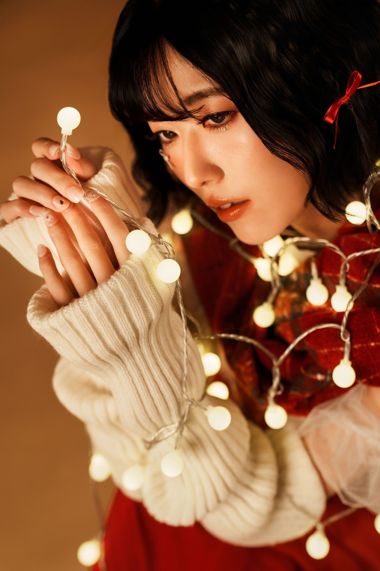 A moody portrait series showing hands holding glowing string lights against a warm brown background.