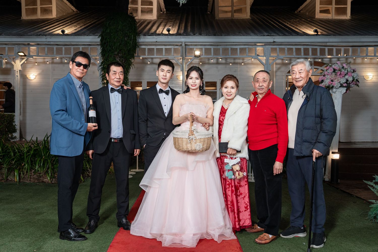 Wedding guests gather outside a historic building for evening portraits at an elegant celebration.