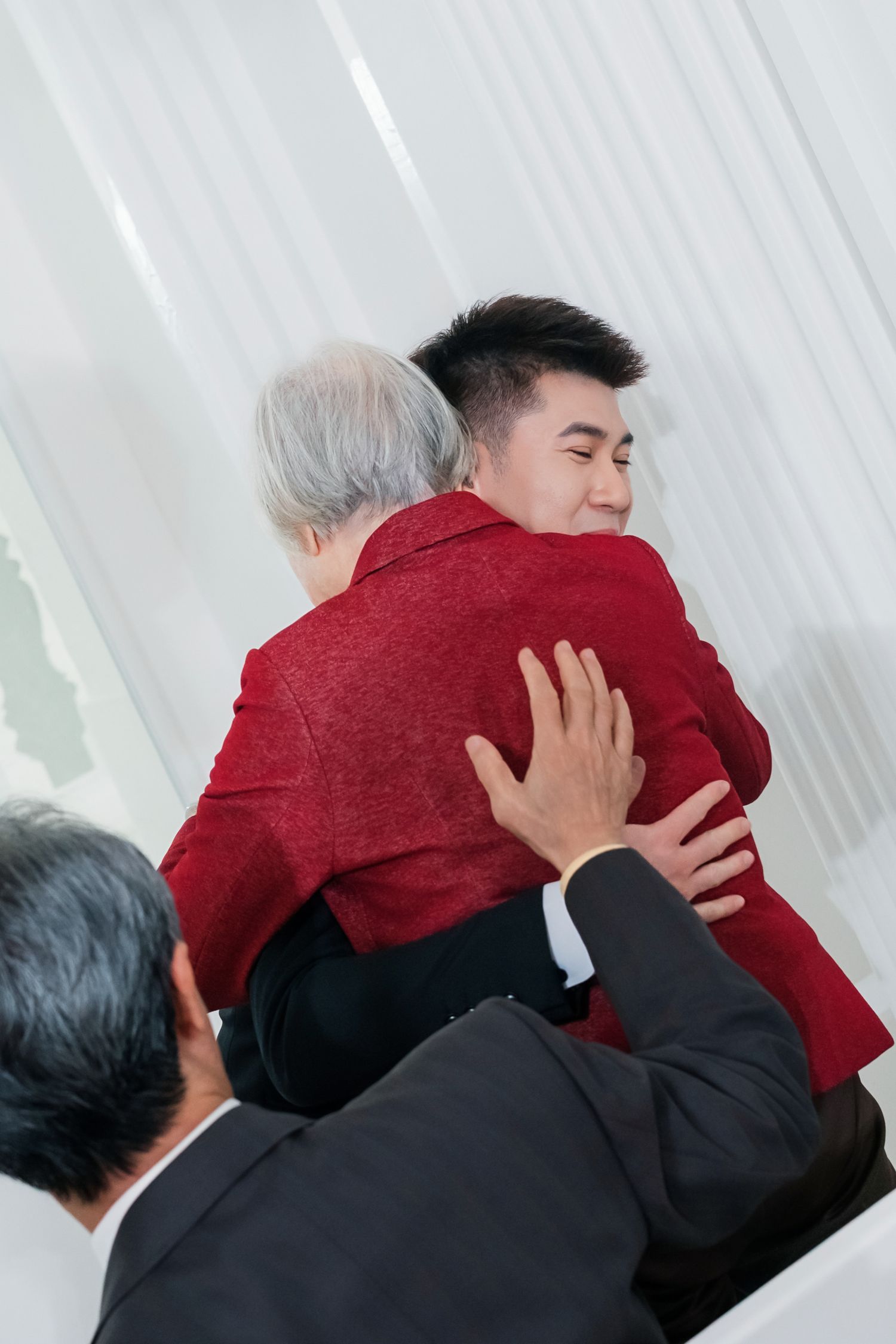 Two people embrace emotionally in a sequence of photos showing a warm hug against a white background.