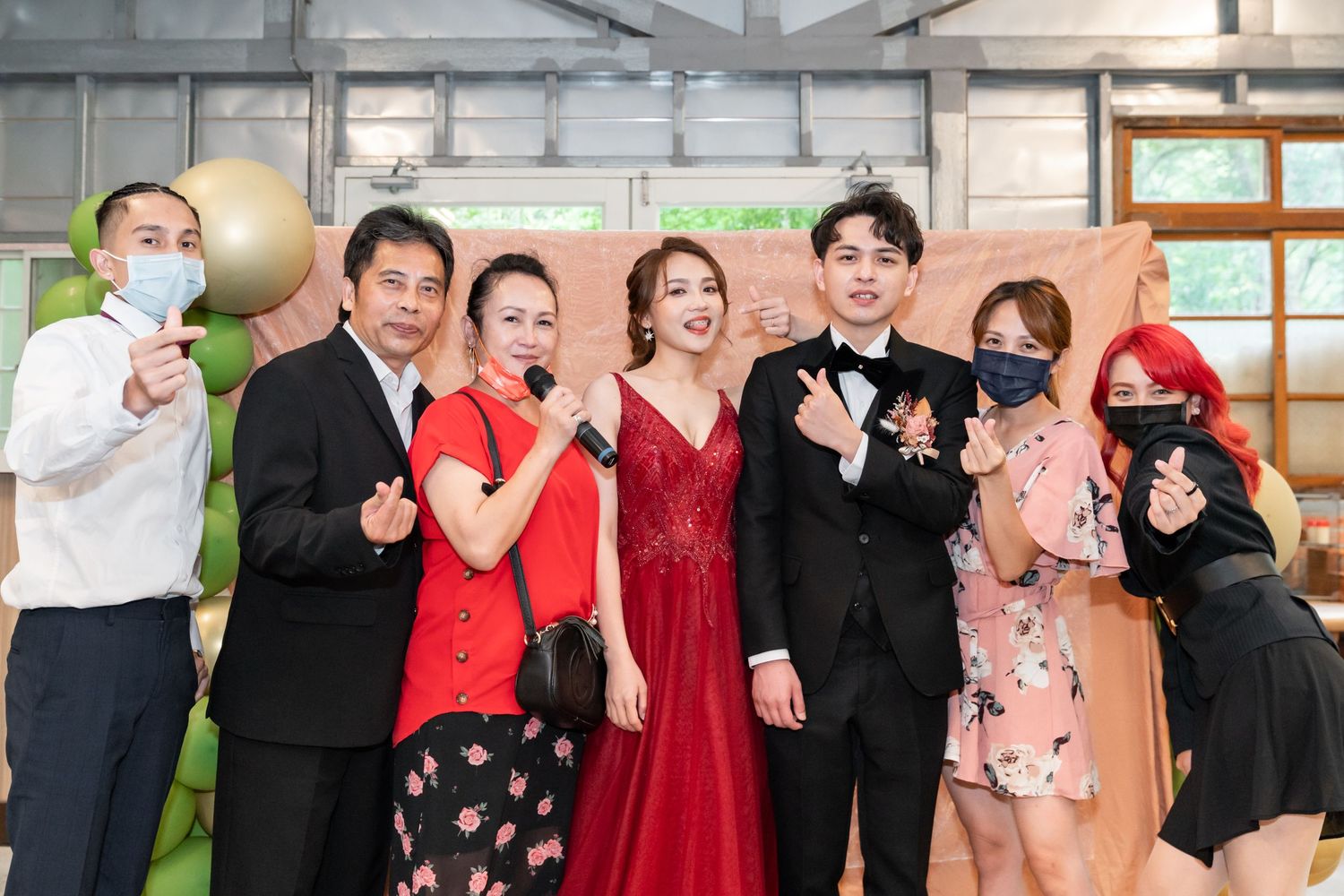 A small group in formal attire poses together at an indoor celebration.