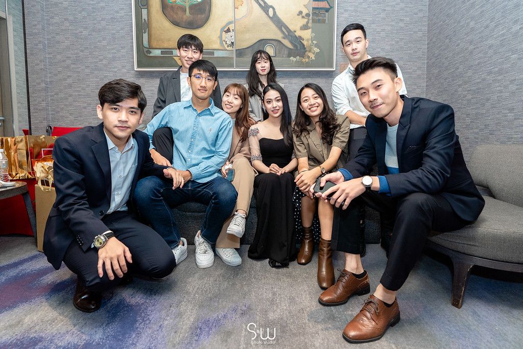 Group of formally dressed friends gathered on a couch for a wedding celebration photo.