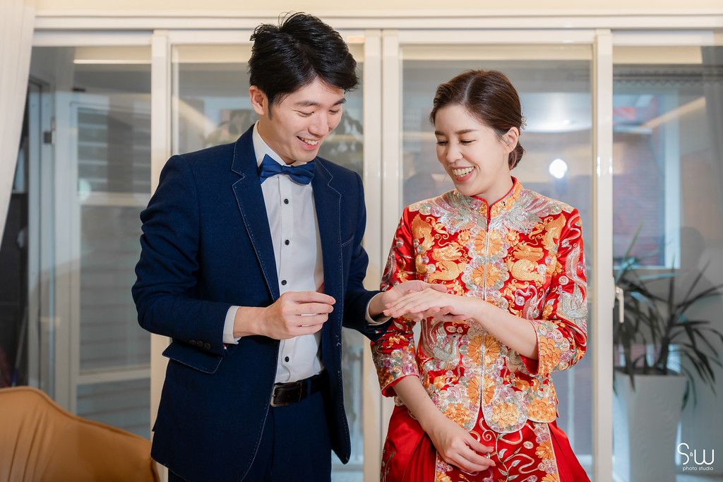Wedding couple in traditional Chinese attire sharing smiles during their ceremony.