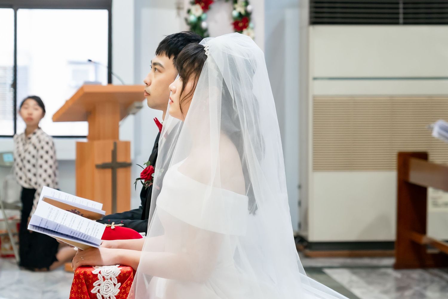 Bride in white veil participates in church wedding ceremony.
