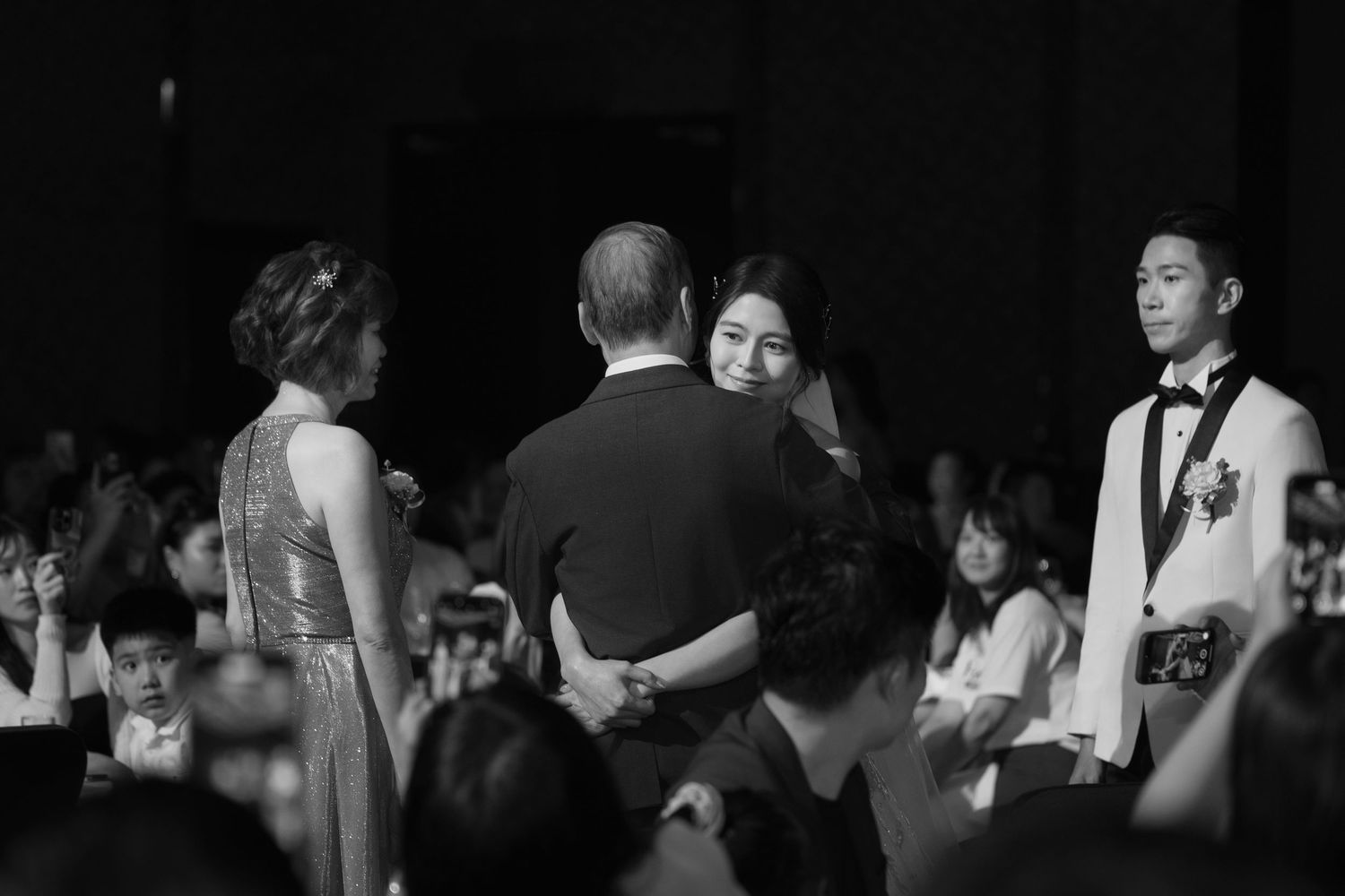 Black and white photo of wedding reception guests gathered in formal attire during an elegant celebration.