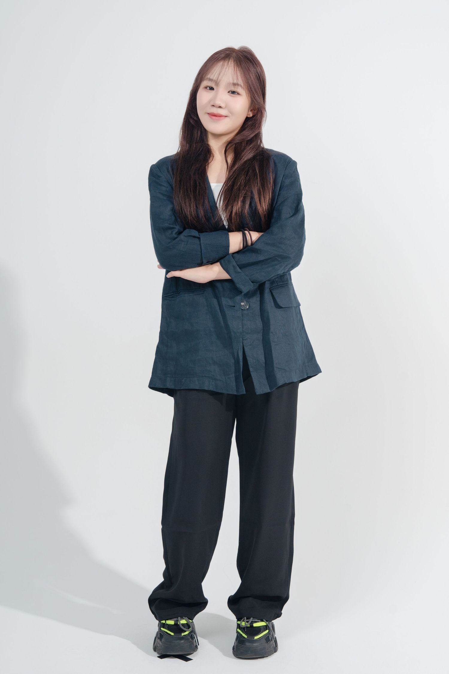 A person in an oversized dark business suit strikes playful poses against a white background.