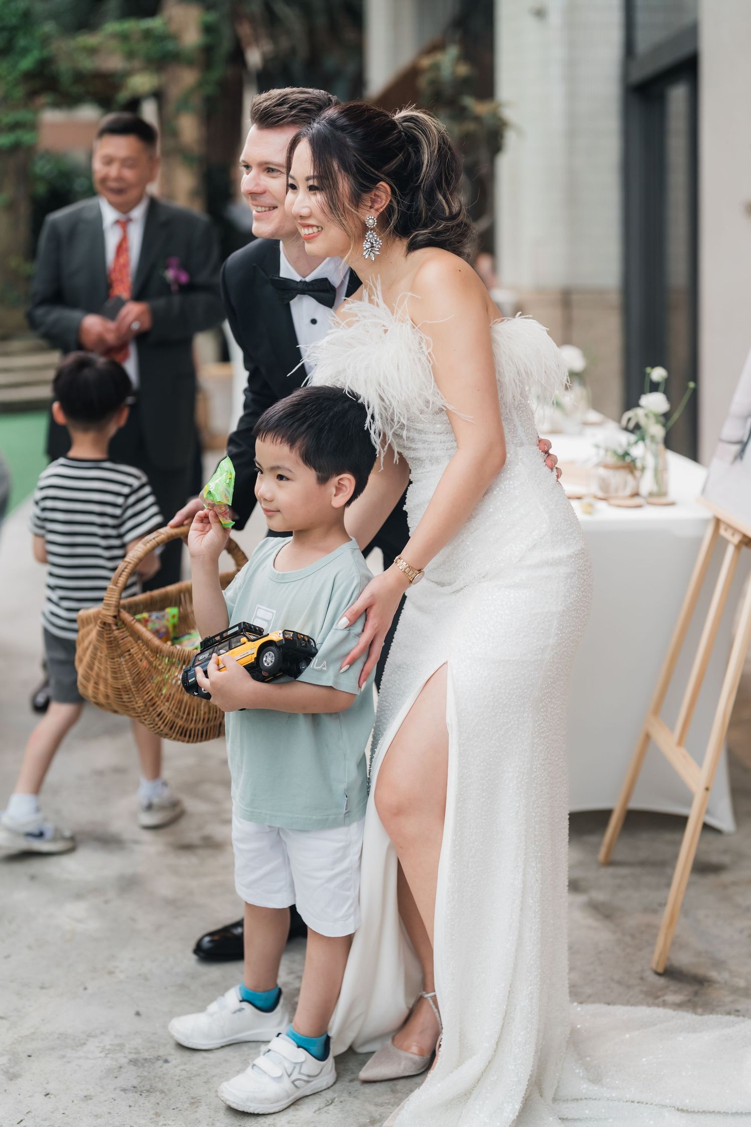 Wedding party interacts with young children enjoying refreshments during an outdoor reception celebration.